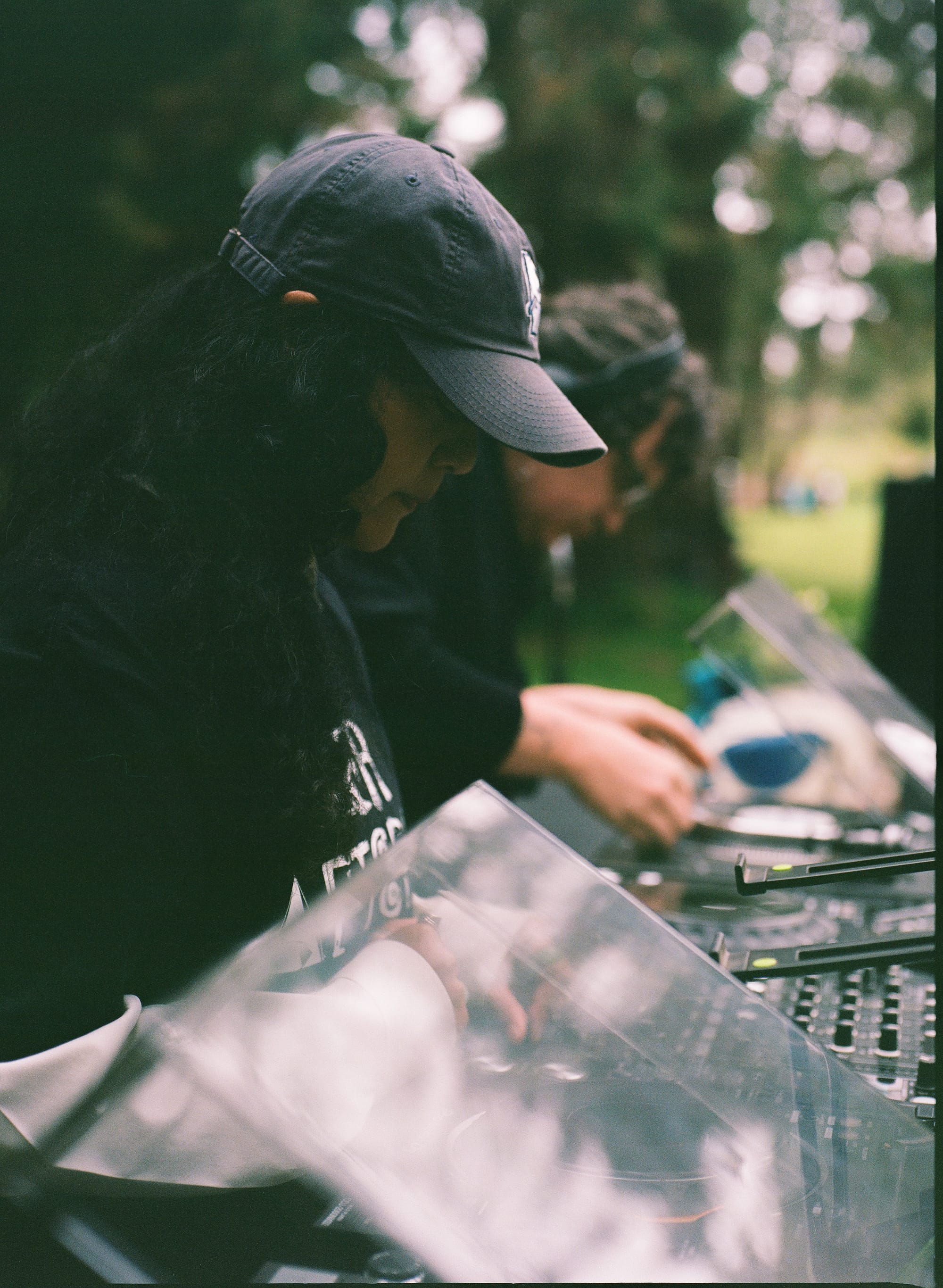 Two people playing records on turntables in an outdoor setting.