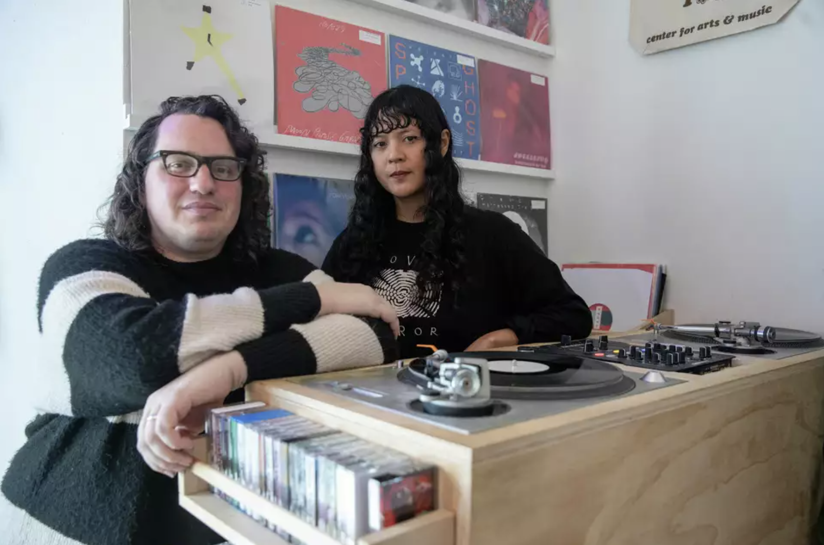 Two people stand beside each other in a small DIY record store.